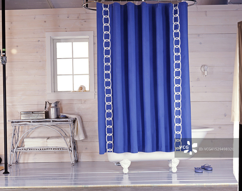 带蓝色浴帘的爪足浴缸位于乡村浴室中图片素材