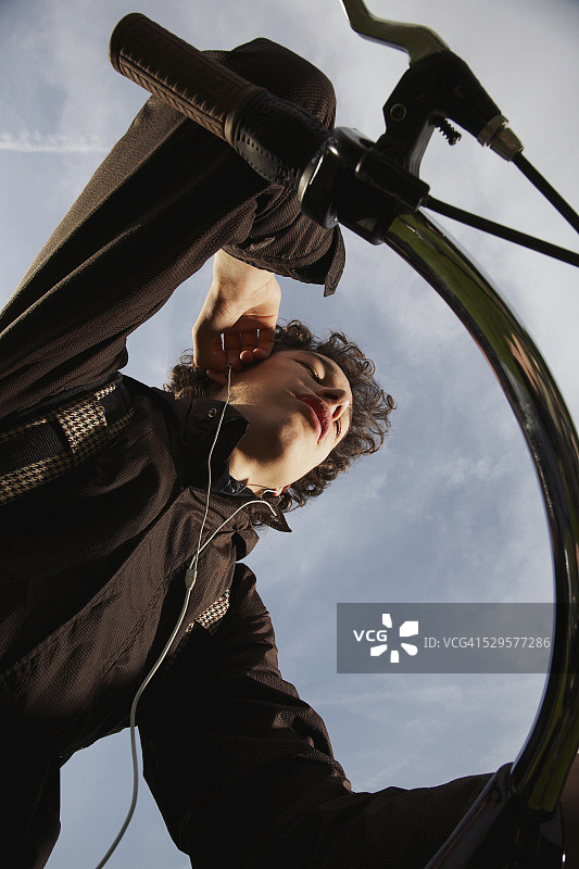 骑自行车并听MP3播放器的青少年男孩图片素材