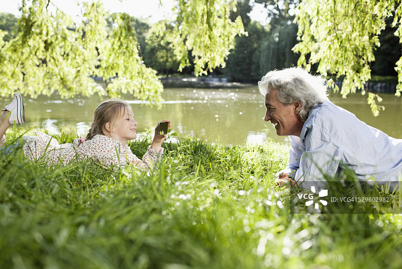 老年男人和他的孙女躺在草地上图片素材