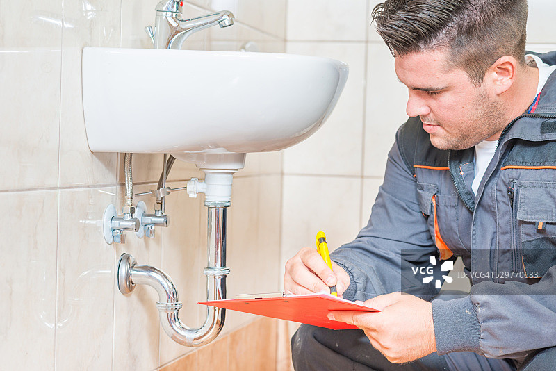 手持写字板的年轻水管工图片素材