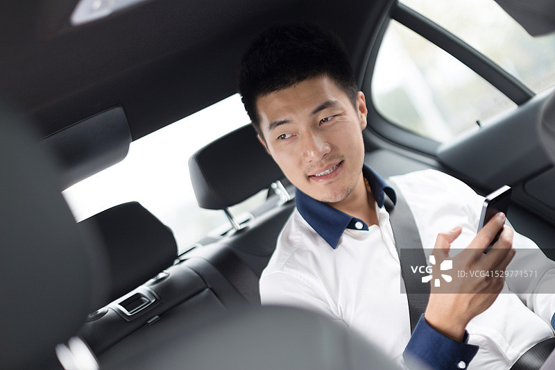在车里使用智能手机的亚洲年轻商人图片素材