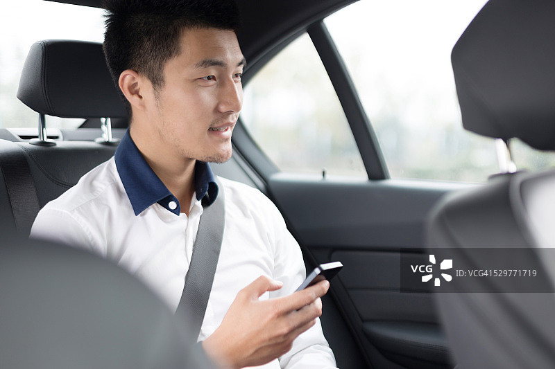 在车里使用智能手机的亚洲年轻商人图片素材