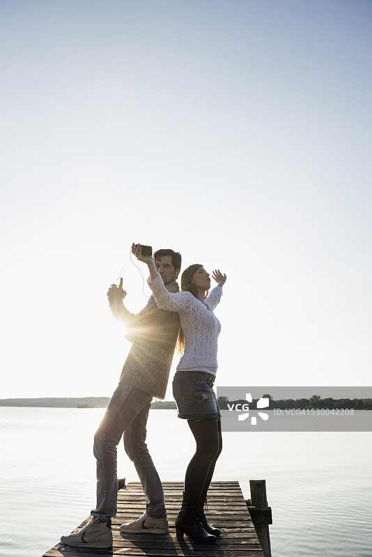 在码头日落时跳舞的年轻情侣图片素材