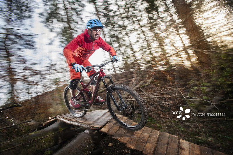 山地自行车手在德国巴伐利亚的森林中穿过木桥图片素材
