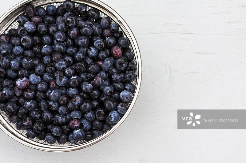 高角度拍摄的装满新鲜蓝莓的筛子图片素材