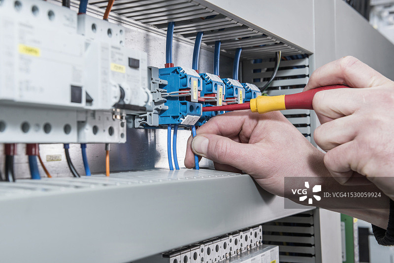 电工在配电熔断器盒中拧紧电缆特写，德国巴伐利亚慕尼黑图片素材