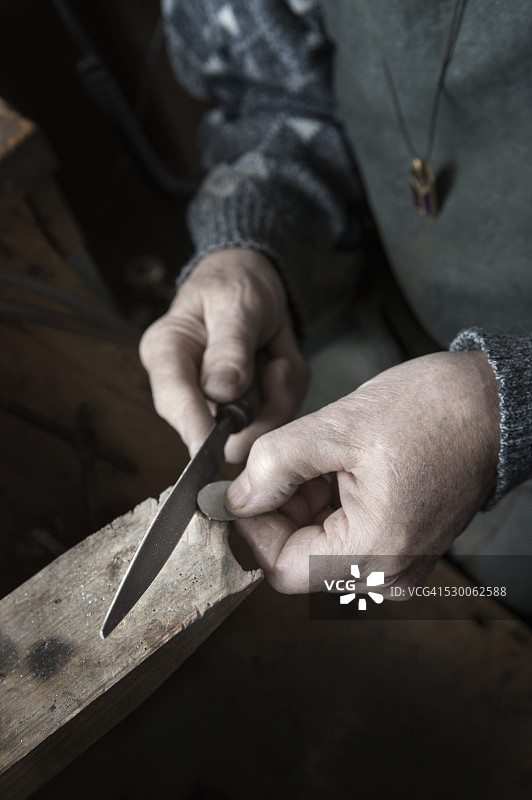 德国巴伐利亚：年长的男性金匠在车间用锉刀打磨水晶图片素材