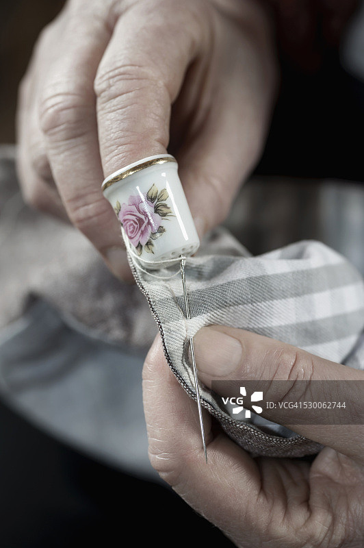 年长的女时装设计师在德国巴伐利亚的工作室里戴着顶针缝纫图片素材