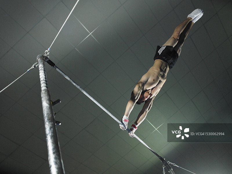 体操运动员在不平衡的双杠上摆动图片素材