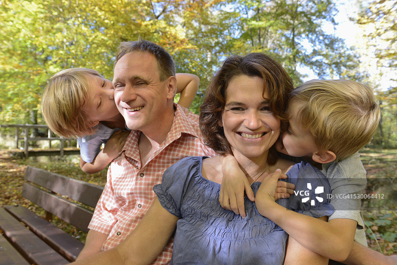 男孩亲吻父母，微笑，德国巴伐利亚图片素材
