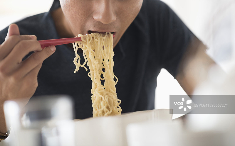 美国新泽西州泽西市，男子用筷子吃面条图片素材