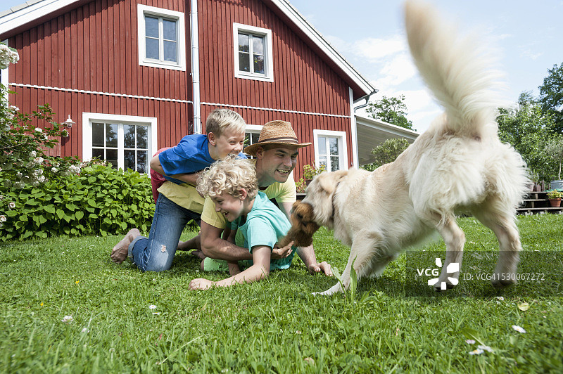 父子在草地上和宠物狗玩耍图片素材