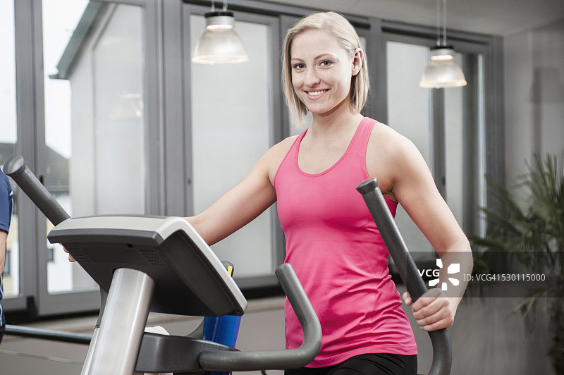 在健身房使用椭圆机的年轻女人图片素材