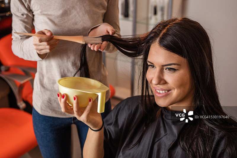 快乐的年轻女子在家染发图片素材