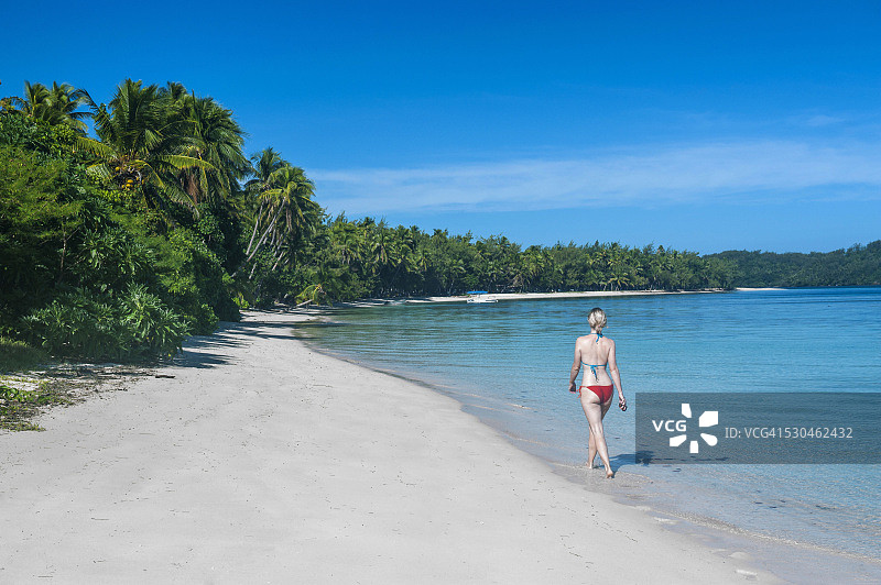 在南太平洋斐济亚萨瓦群岛蓝色泻湖纳努亚莱莱岛的白色沙滩上行走的一位女人图片素材