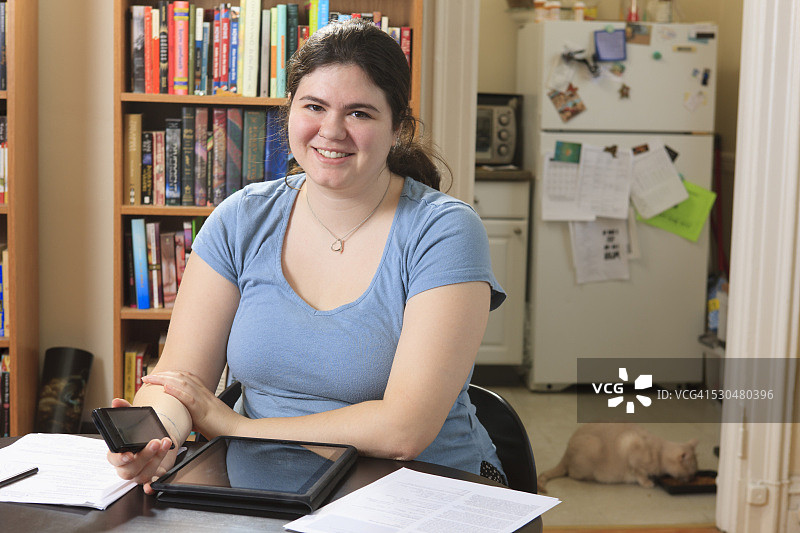 在家用智能手机和平板电脑工作的阿斯伯格综合征女人图片素材