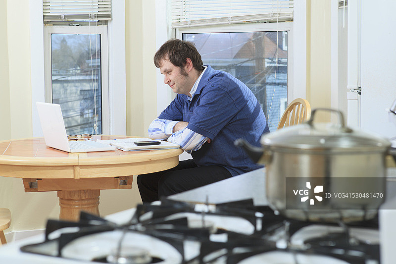 在家中一边做饭一边工作的男人图片素材