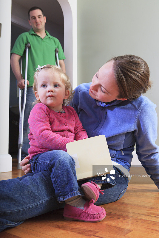 男人在家中与妻子和女儿，做前交叉韧带（ACL）手术后图片素材