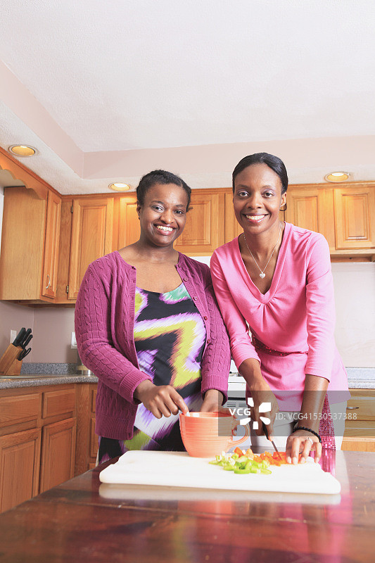 姐妹俩在厨房做饭，其中一个有学习障碍图片素材