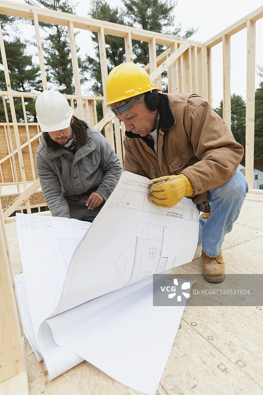 建筑主管与木匠审查房屋设计图图片素材