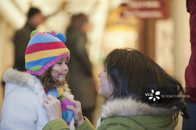 冬天购物时女人为女儿系围巾图片素材