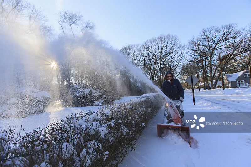 暴风雪后使用吹雪机的中年男人图片素材