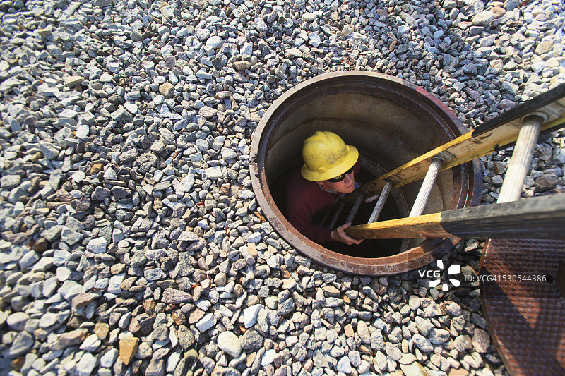 美国麻萨诸塞州布伦特里高压配电站人孔爬梯内的电力工程师图片素材