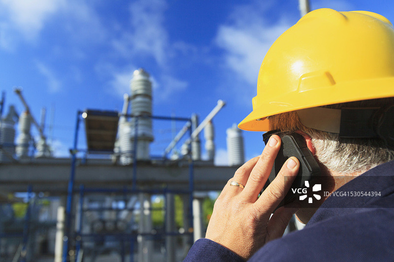 电力工程师在美国马萨诸塞州布伦特里高压配电站用手机通话图片素材