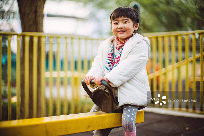小女孩在操场上高兴地玩跷跷板图片素材