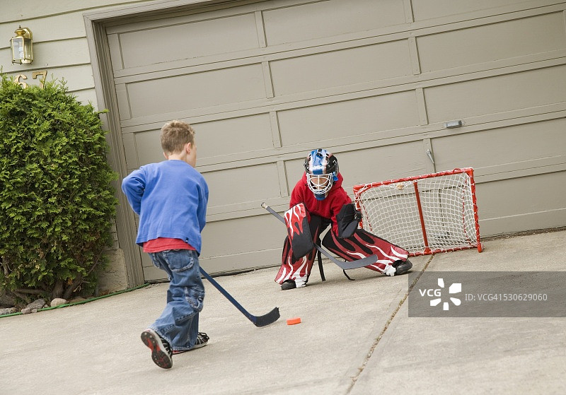 男孩们在车道上玩曲棍球图片素材