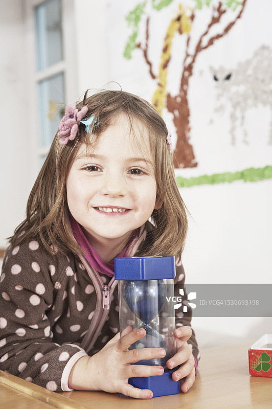 在幼儿园玩沙漏的小女孩，德国巴伐利亚州科特盖斯林图片素材