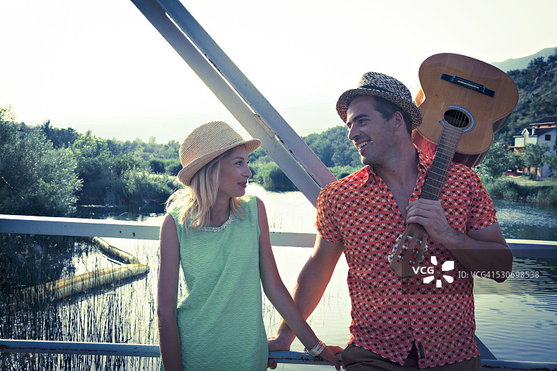 克罗地亚达尔马提亚一对年轻夫妇在人行桥上，男子抱着吉他图片素材