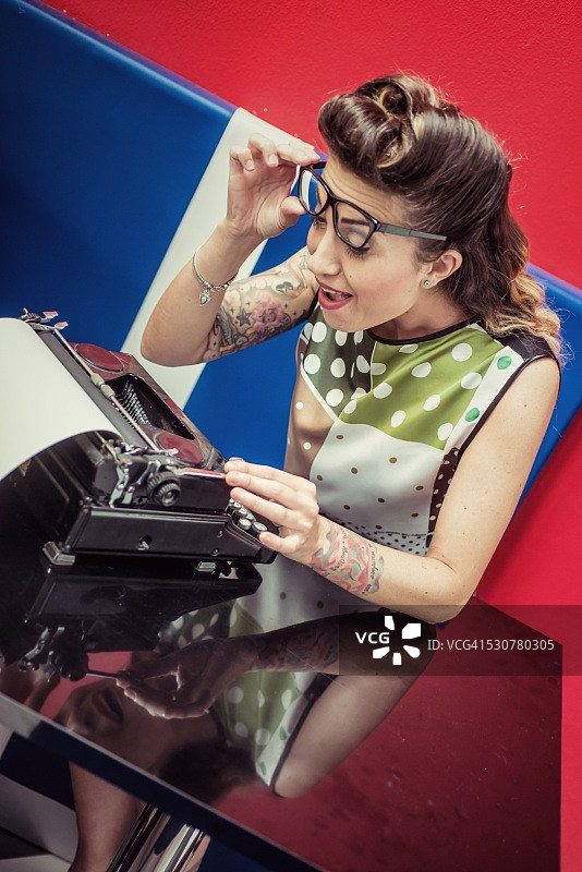 惊讶的复古风格女人使用老式打字机图片素材