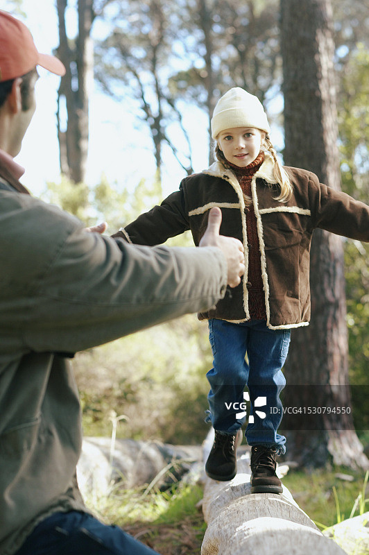 在原木上向女儿伸出手的男人图片素材