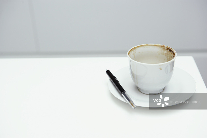 放在茶托上的杯子和钢笔图片素材