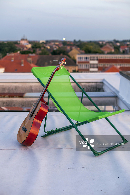 靠在屋顶露台日光躺椅上的吉他图片素材