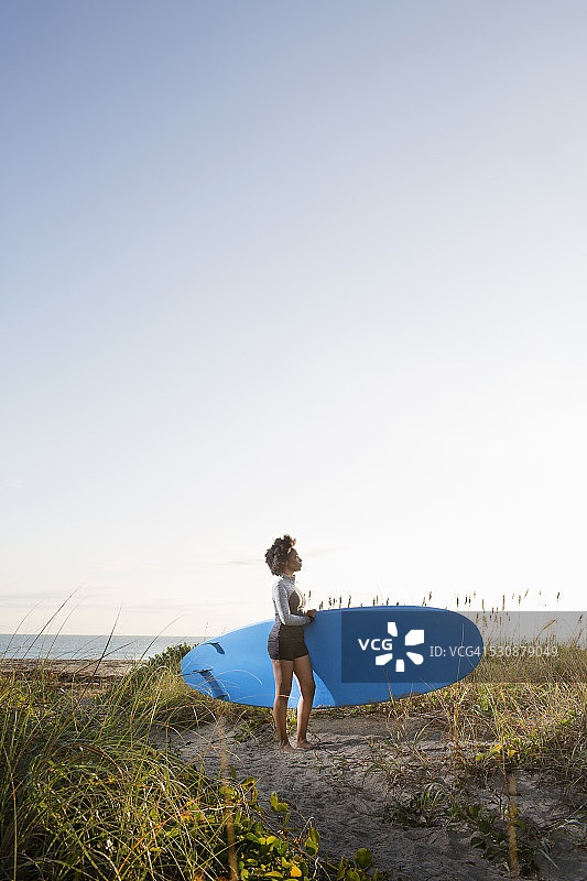 在海滩上拿着桨板的年轻女人图片素材