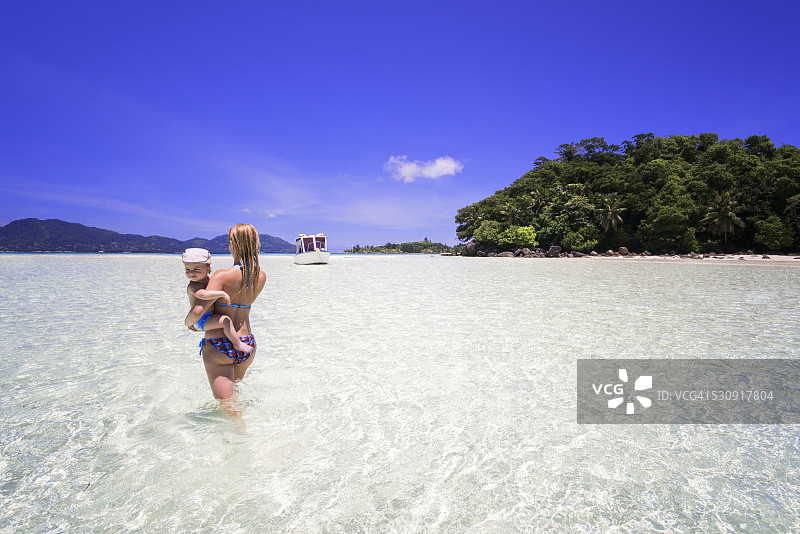 母亲带着儿子在海边行走背影图片素材