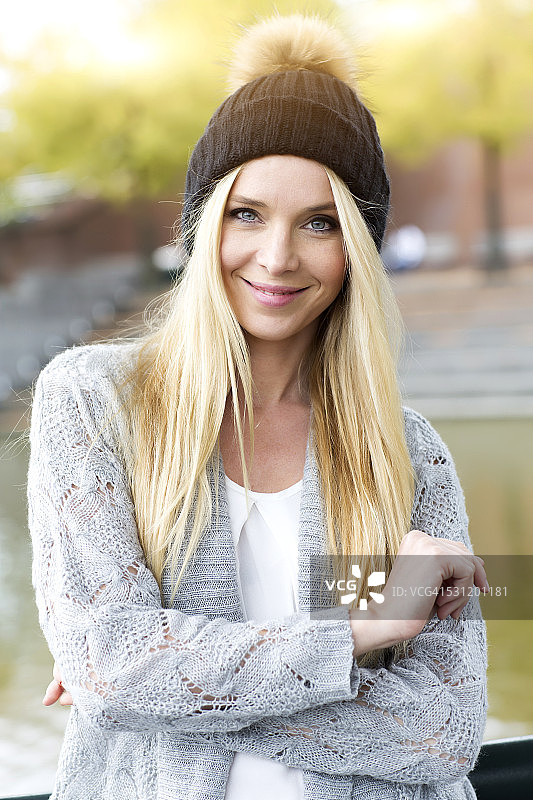 戴着绒球帽和开衫的微笑年轻女人肖像图片素材