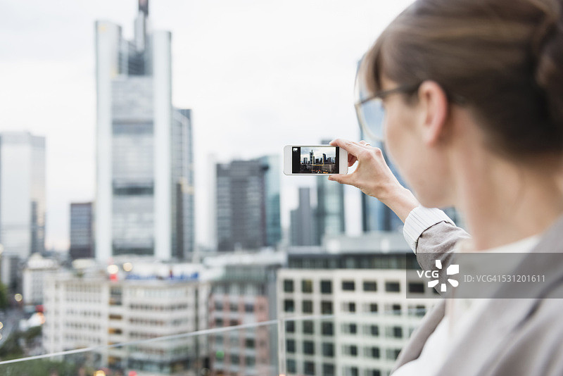 德国黑森州法兰克福：用智能手机拍摄天际线的女人图片素材