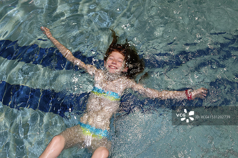在泳池里仰泳的微笑女孩图片素材
