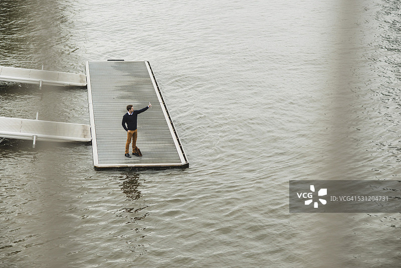 德国黑森州法兰克福一位年轻男人站在码头上用平板电脑自拍图片素材