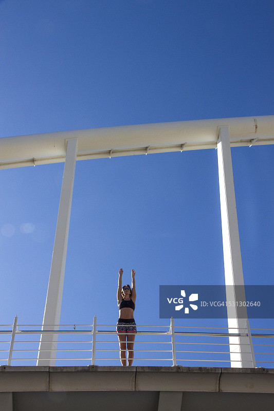 在城市桥梁上锻炼前伸展身体的女人图片素材
