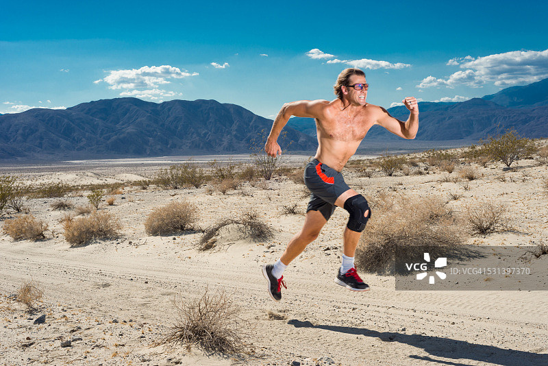 戴着护膝在沙漠中跑步的男人图片素材