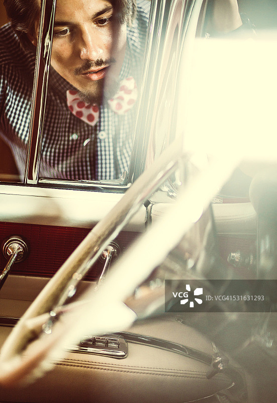 年轻优雅的男人看着老式老爷车的内部图片素材