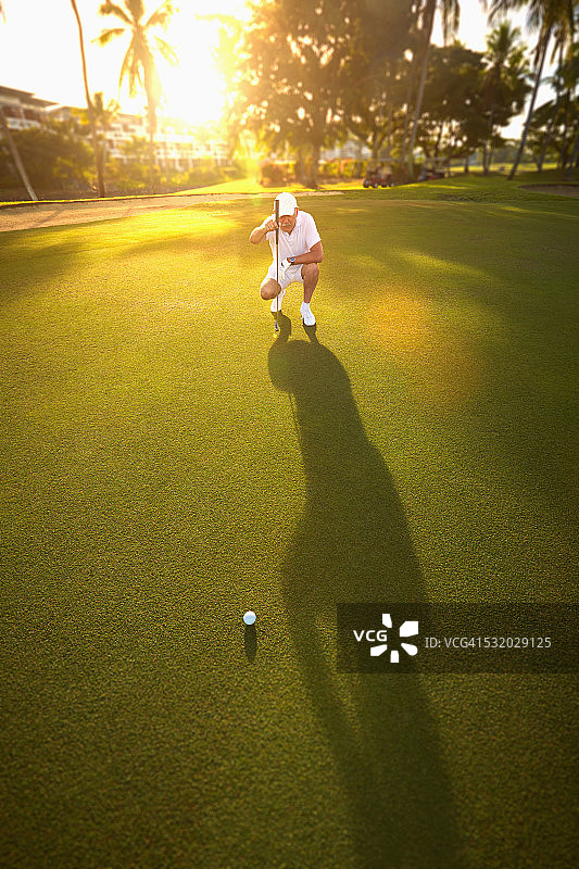 白人高尔夫球手在果岭上准备击球图片素材