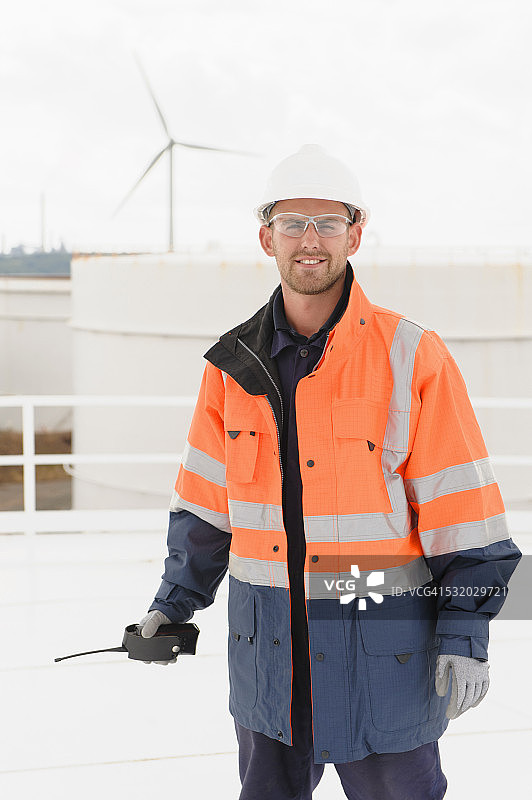 白人技术员在储油罐上拿着对讲机图片素材