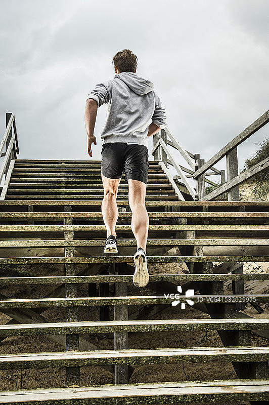 在海滩上攀登木板路楼梯的白人跑步者图片素材