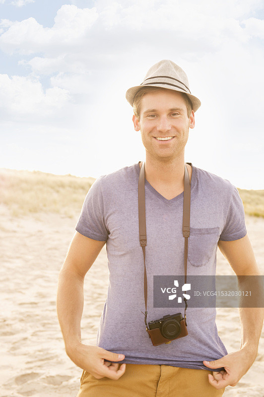 在海滩上戴着相机带的白人男子图片素材