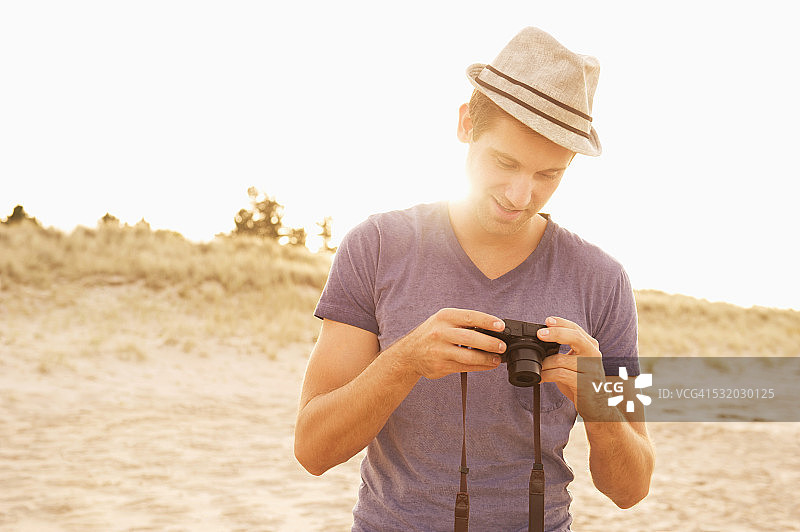 在海滩上用数码相机查看照片的白人男人图片素材